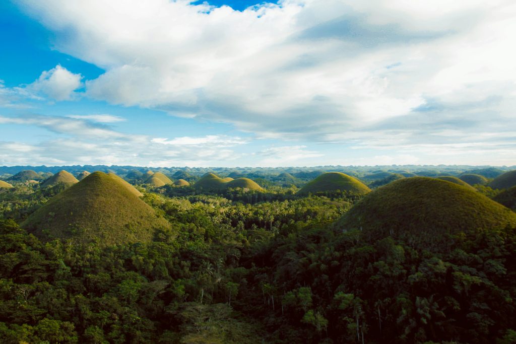 Scenic aerial view of the iconic Chocolate Hills in Bohol, lush landscape under a clear blue sky.