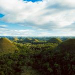 Scenic aerial view of the iconic Chocolate Hills in Bohol, lush landscape under a clear blue sky.